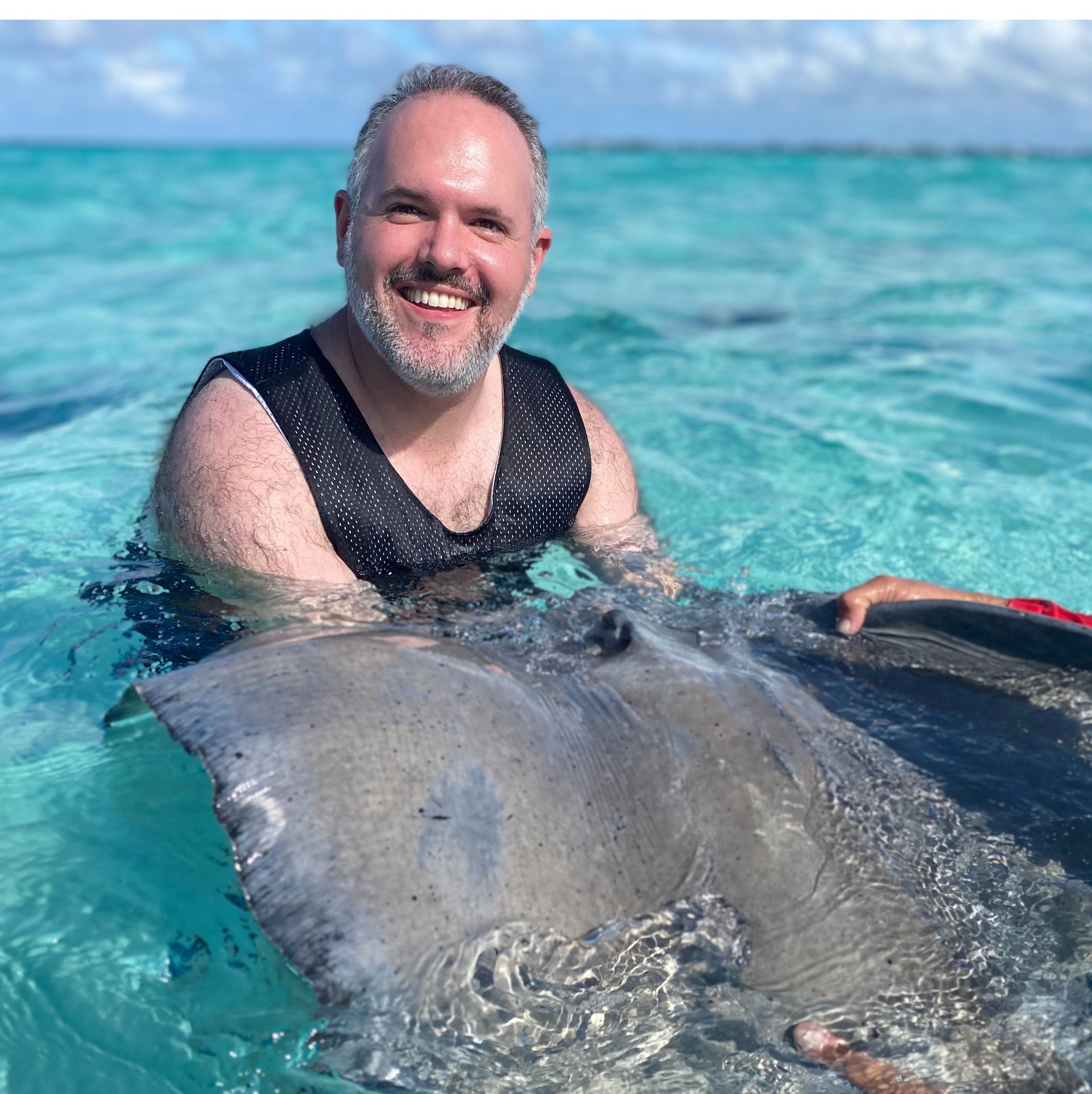 Zachary smiling while swimming with a stingray